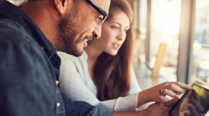 Couple Using Digital Tablet At Cafe