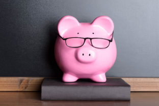 Piggy Bank With Eye Glasses On Book